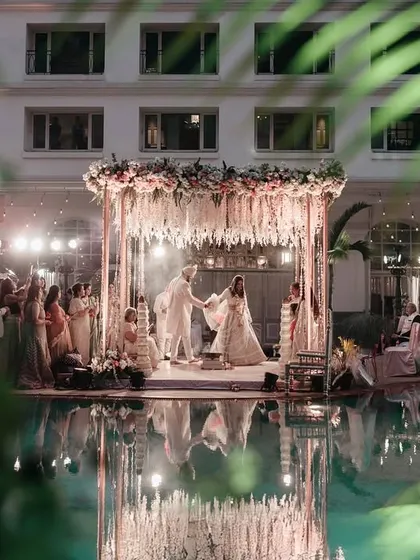 A stunning view of the poolside mandap at the Hilton, Mumbai, with the ceremony's reflection captured in the water, adding a layer of magic.