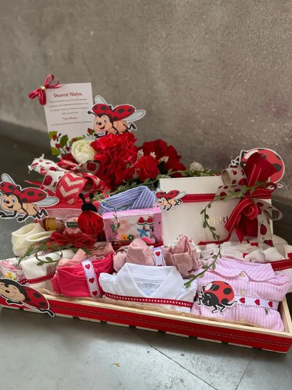 A closer view of our ladybug-themed baby hamper, showcasing the neatly rolled baby clothes, themed ribbons, and a personalized card, ready to be gifted.
