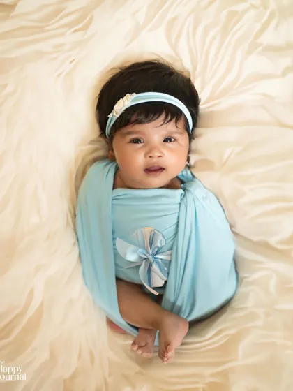 Simply sweet and swaddled in blue. This classic newborn pose highlights the baby's delicate features and peaceful expression, creating a timeless memory.