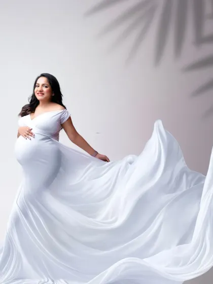 A graceful pose with a sweeping white train. The contrast of the simple gown with the dramatic fabric creates a visually stunning and elegant maternity portrait.