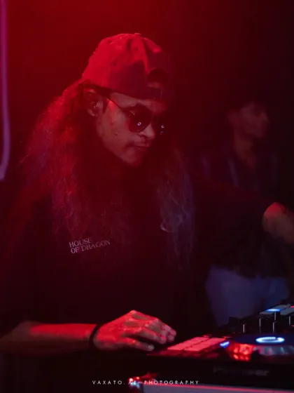 A dark, red-lit photo of me focused on my DJ controller.