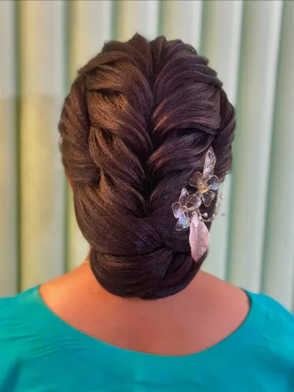 An intricate braided updo with a modern twist. The crystal and feather accessory adds a touch of contemporary glamour to this beautifully structured bun.