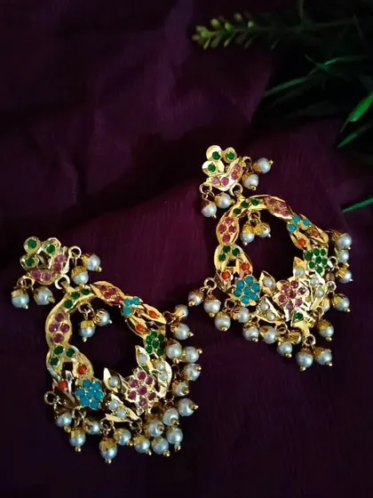 The earrings from the limited edition "Triveni" necklace set. The colourful, crescent-shaped design with pearl drops makes them a vibrant and festive accessory.