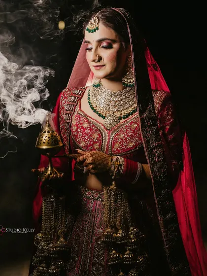 A dramatic and moody portrait of the bride in her red lehenga, holding a traditional incense burner.