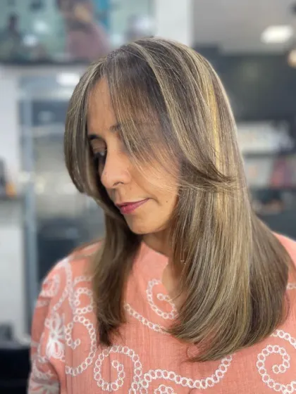 A side profile of a sleek, layered cut with face-framing bangs and beautiful highlights. One glance is all it takes.