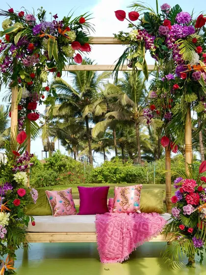 A beautiful swing seat for the bride, framed with lush tropical flowers and greenery, set against the palm trees of Goa.