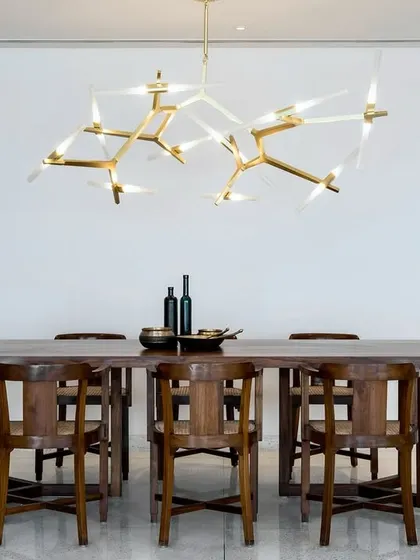 The dining area in the Terrazzo Residence is anchored by a striking modern chandelier. We kept the surrounding decor minimal to draw attention to the custom wooden dining set and the clean, white space.