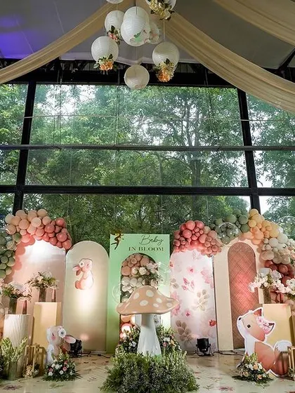 A wider view of the enchanted garden stage, showing the full scope of the decor against the venue's large glass windows. The setup included a white picket fence and glowing butterfly accents to complete the fairytale look.