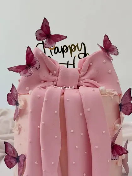 A close-up of the big pink bow and butterfly details on this trendy cake.