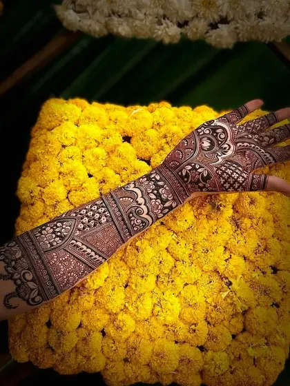 A beautiful, full-arm design photographed against a backdrop of marigold flowers. The intricate patterns are perfect for any festive occasion.
