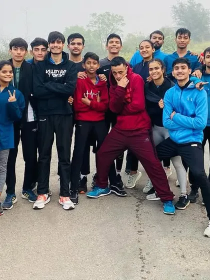 The team poses for a group photo after a tough outdoor running session. The exhaustion is mixed with a sense of accomplishment and togetherness.