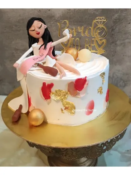 A fun and cheeky "Bride to be" cake for a bachelorette party. It features a handcrafted fondant figurine of the bride enjoying her last moments of single life, complete with mini champagne bottles.