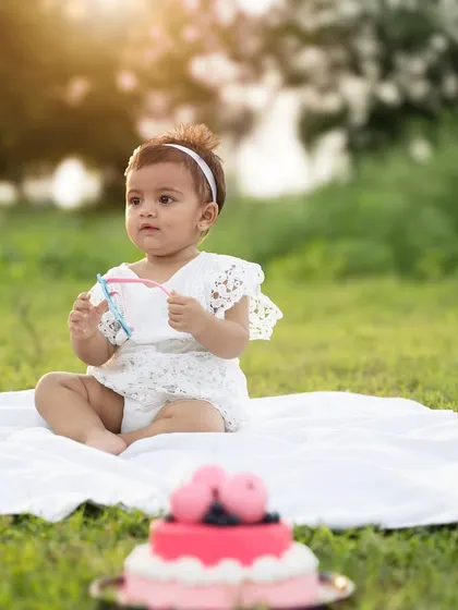 A serene outdoor cake smash session at sunset. The golden light adds a warm, magical glow to this special first birthday memory.