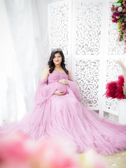 A vision in lavender. This portrait captures the mom-to-be seated gracefully, her voluminous tulle gown creating a soft and dreamy effect.