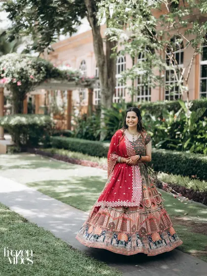 A beautiful solo portrait of the bride, Shubhi, walking through the resort gardens. Her colorful lehenga looks stunning against the green background.