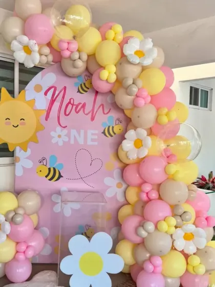 "Our Little Honey Bee" theme for Noah's first birthday. This adorable setup uses yellow, pink, and pastel balloons with cute bee and daisy accents for a sweet and sunny celebration.