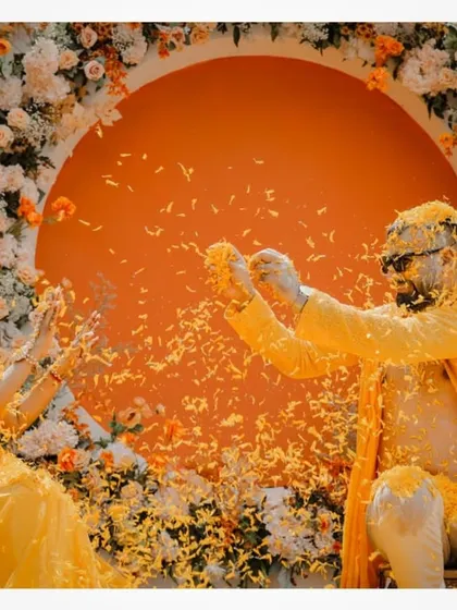 A playful moment with the couple showering each other with flower petals at their Thailand Haldi.