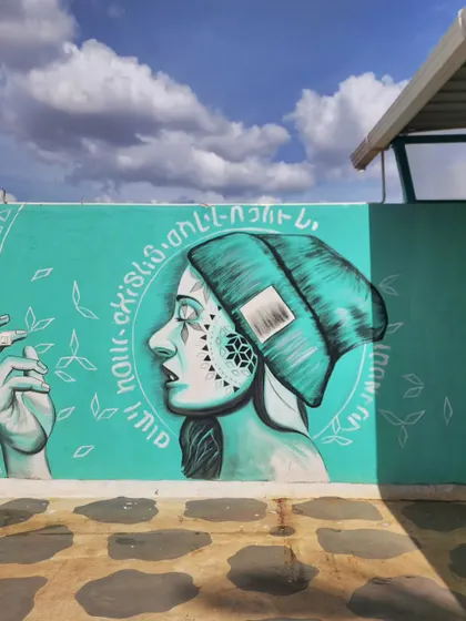 On another exterior wall at The Secret Place, we painted this serene street art piece featuring a woman in profile surrounded by delicate leaf patterns.