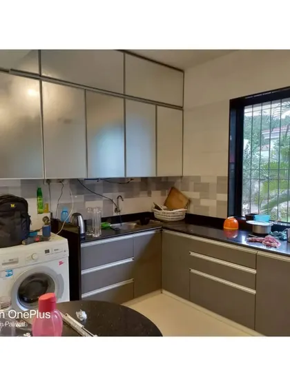 Another view of Mr. Maheshwari's kitchen, showing the placement of the washing machine under the counter to save space. The frosted glass profile shutters on the upper cabinets offer a lighter feel.