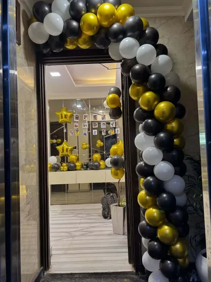 A stylish black, white, and gold balloon arch creates an inviting entrance for a house party. This decoration immediately sets a celebratory mood for guests as they arrive.