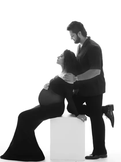 A powerful and artistic pose. The contrast in this black and white image highlights the beautiful curve of her bump and the supportive presence of her partner.