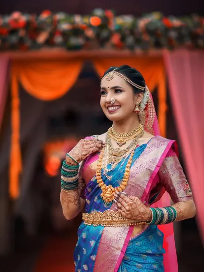 A stunning portrait of a South Indian bride in her magnificent Kanjeevaram saree, showcasing her intricate gold jewelry and radiant smile.