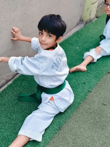 A young boy works on his splits against the wall. This is a great way to safely improve flexibility over time.