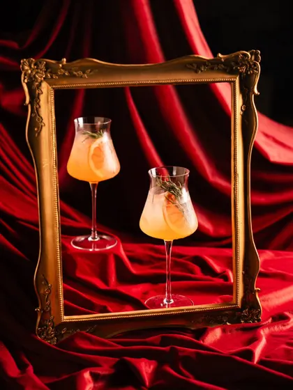 A creative cocktail shot for Amelia, using a vintage gold frame against a rich red velvet backdrop. This framing technique creates a sense of art and luxury, presenting the drinks as masterpieces.