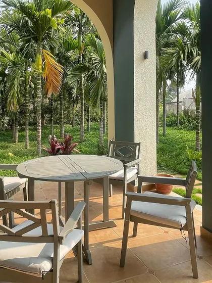 The arched veranda of a farmhouse on the outskirts of Bangalore. This space is designed for enjoying the view of the surrounding palm grove, providing a shaded, breezy spot for relaxation.