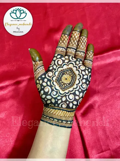 A beautiful cutwork design with a central floral mandala. The surrounding swirls and leaves are filled in with dark henna, making the central pattern stand out.