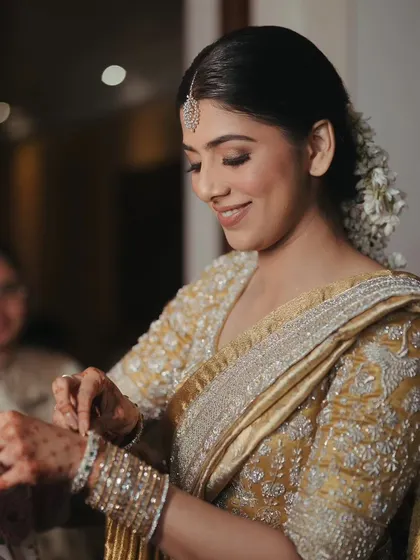 A sweet moment of the bride getting help with her bangles, surrounded by the warmth of family.