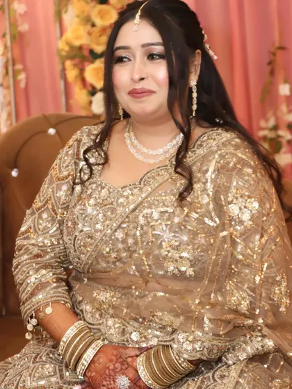 A beautiful seated portrait of the engagement bride in a golden lehenga, looking serene and elegant.