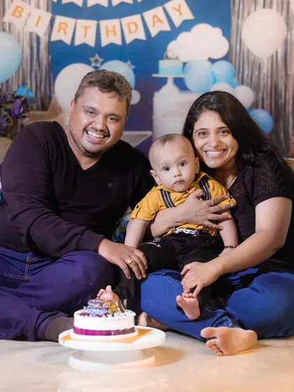 A happy family portrait taken during a studio cake smash session, with a beautiful blue and silver themed backdrop.