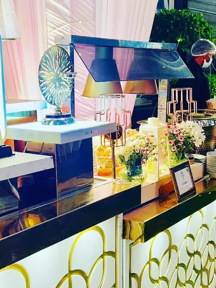 An elegant and modern buffet line with gold and white accents, perfect for a chic daytime event. The setup includes stylish lamps and decorative elements that elevate the presentation from a simple meal to a design feature.