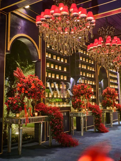 A closer view of the entrance corridor, showing the cascading red florals on mirrored tables and the walls of flickering candles, creating a path of romance and opulence.