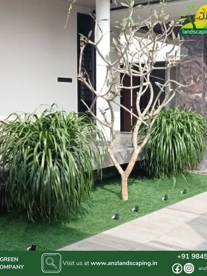 This minimalist garden design uses a combination of artificial turf, a single specimen tree, and lush bushes to create a modern and low-maintenance green space.