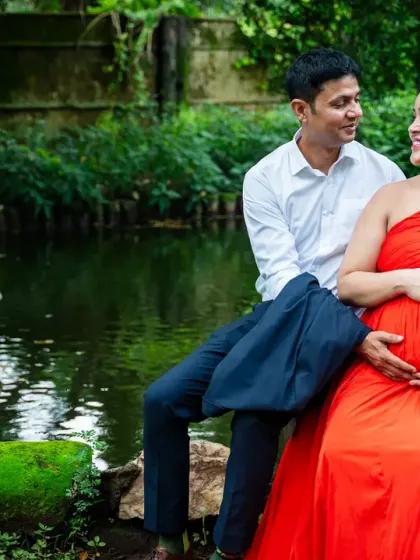 Even on a cloudy day, the warmth of an expecting couple shines through. This candid moment was captured by a pond, with the mom-to-be's bright orange dress adding a pop of color to the serene landscape.