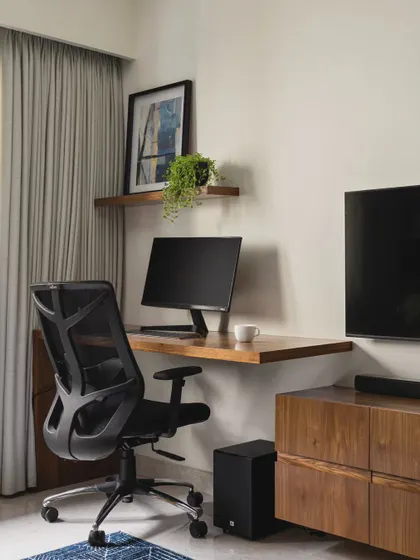 Even a small corner can become a functional workspace. Here, a simple floating wooden desk and shelf provide a dedicated spot for work without taking up much floor space. It's an efficient use of space in a multi-purpose room.
