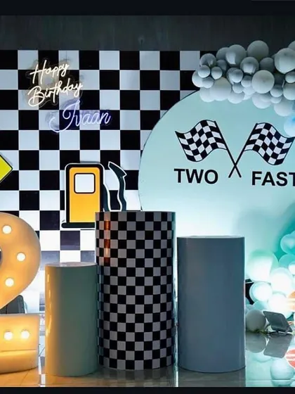 A "Two Fast" car race theme for a second birthday. I used a checkered flag backdrop, a custom "Two Fast" sign, and props like a gas pump and traffic light to create a fun racetrack environment, complete with a large light-up number 2.