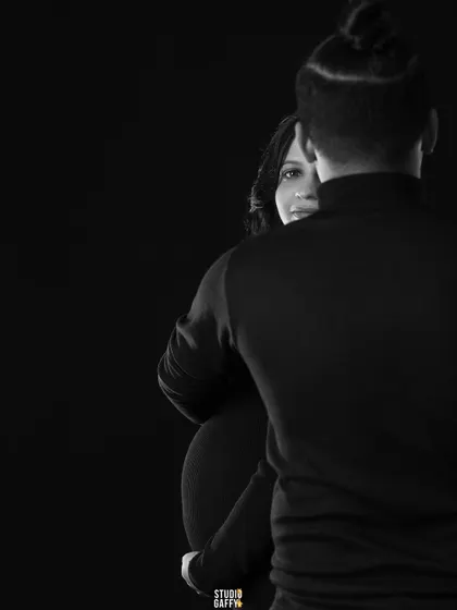 An artistic and mysterious monochrome portrait, with the mother-to-be peeking from behind her partner.