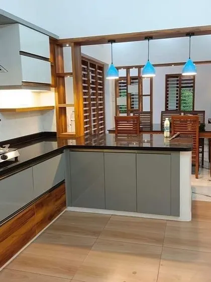 An open kitchen design where the counter extends to form a breakfast bar, connecting directly to the dining area. The wood and grey color scheme creates a warm and modern feel.