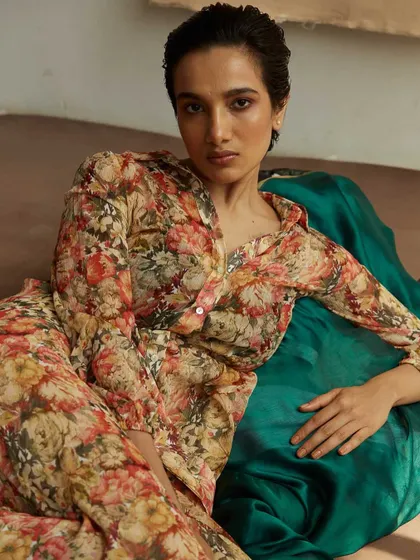 Using layers of paper and fabric to create a textured, artistic backdrop. The floral pattern of the outfit contrasts beautifully with the emerald green cloth, making for a rich, painterly portrait.