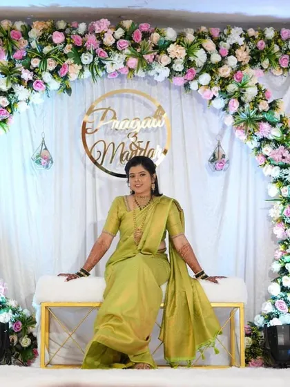 The bride posing on the stage we created for her engagement. The white sofa and floral arch with a custom name hoop make for a perfect solo portrait spot.