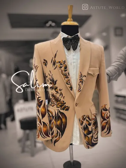 A beige blazer on a mannequin, brought to life with bold, hand-painted abstract floral designs. This is a perfect piece for a daytime event or a destination wedding.
