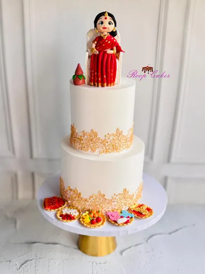 A traditional welcome for a new baby. This Dohale Jevan (Maharashtrian baby shower) cake features a beautiful hand-modelled figure in a classic red saree, surrounded by intricate gold stenciling and traditional offerings.