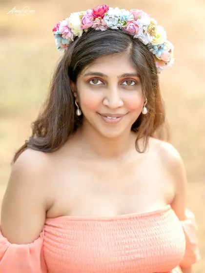 A lovely close-up portrait focusing on the mother's happy and serene expression. The floral crown adds a touch of bohemian charm to her look.