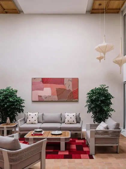 **Cocoon House, Ahmedabad:** This double-height living area is designed to feel grand yet inviting. We used soft textiles, natural greenery, and curated artwork to add warmth and personality, while the high ceiling provides a sense of spaciousness and light.