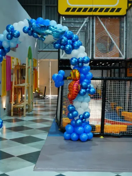 An enchanting 'Under the Sea' birthday theme, complete with blue and white balloons, shark and octopus cutouts, and seahorse details to make a magical underwater world.
