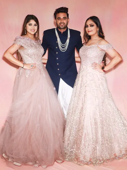 A stylish trio ready for a celebration. The gentleman in the center is wearing a navy blue Indo-western jacket, flanked by two ladies in beautiful rental gowns.
