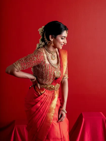 A joyful smile from the bride, capturing the emotion of her special day. The red and gold ensemble glows, highlighting the timeless beauty of traditional South Indian bridal attire.
